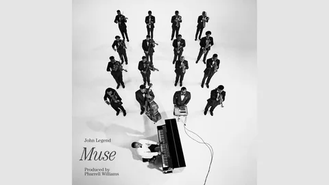 John Legend Muse cover: a man at a piano seen from above, facing rows of suited musicians on a white floor